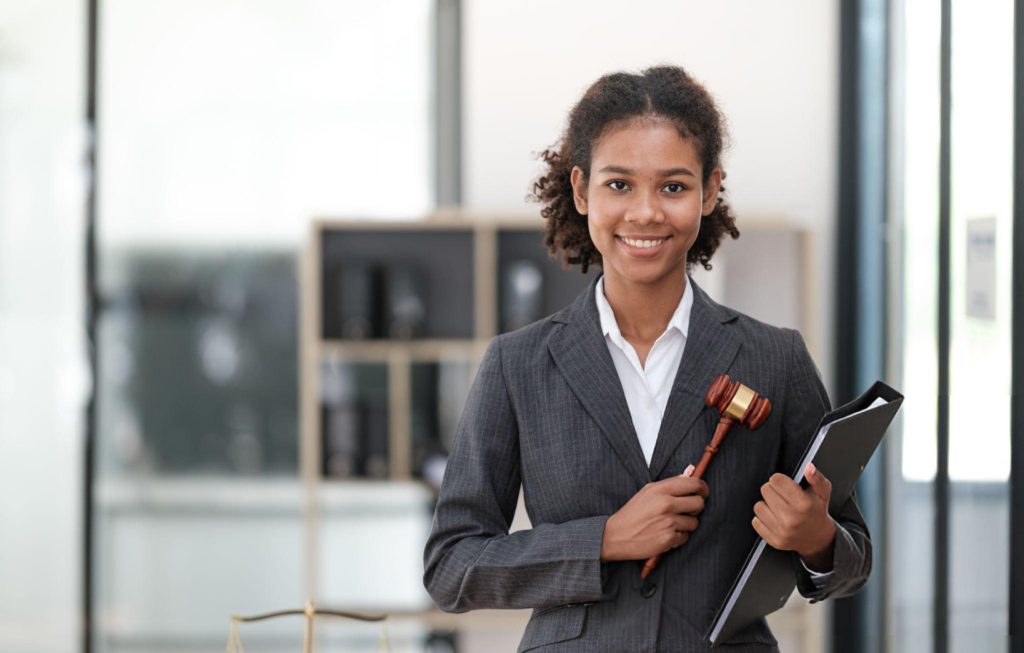 A woman in a suit holds a gavel and a folder, standing in an office with shelves and legal scales—representing the professionalism of Houston divorce lawyers.