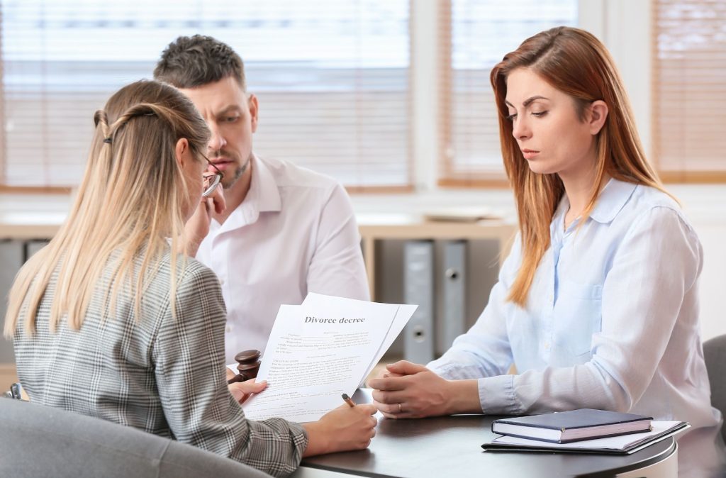 A man and a woman sit across from a legal professional in a Houston office, as one of the city's leading female divorce lawyers discusses the details of their divorce decree.