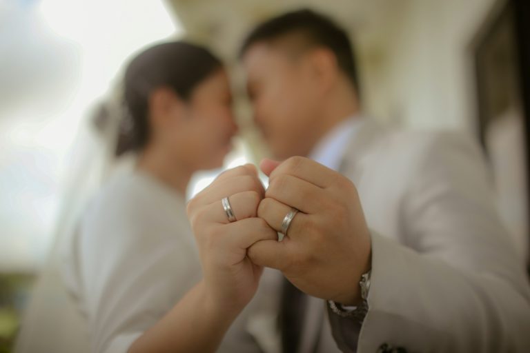 Close-up of two people linking pinky fingers, both wearing wedding rings, symbolizing trust and unity—an intimate moment that highlights the importance of prenuptial agreements for couples preparing for marriage.