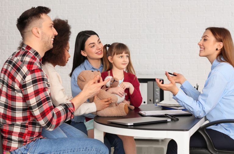 A family of four, including two adults and two children, sits at a desk across from a professional woman during a consultation with financial mediators Houston.