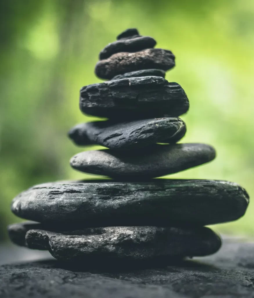 A stack of smooth, flat stones balanced on top of each other with a blurred green background.