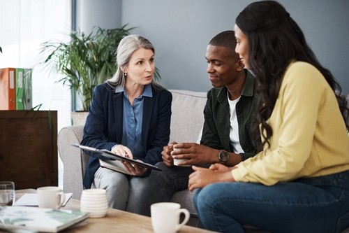 Couple reviewing documents with financial advisor at desk during consultation meeting